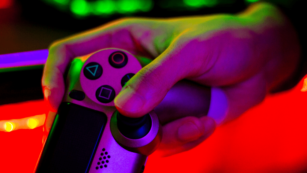 A person holding a video game controller in front of neon lights