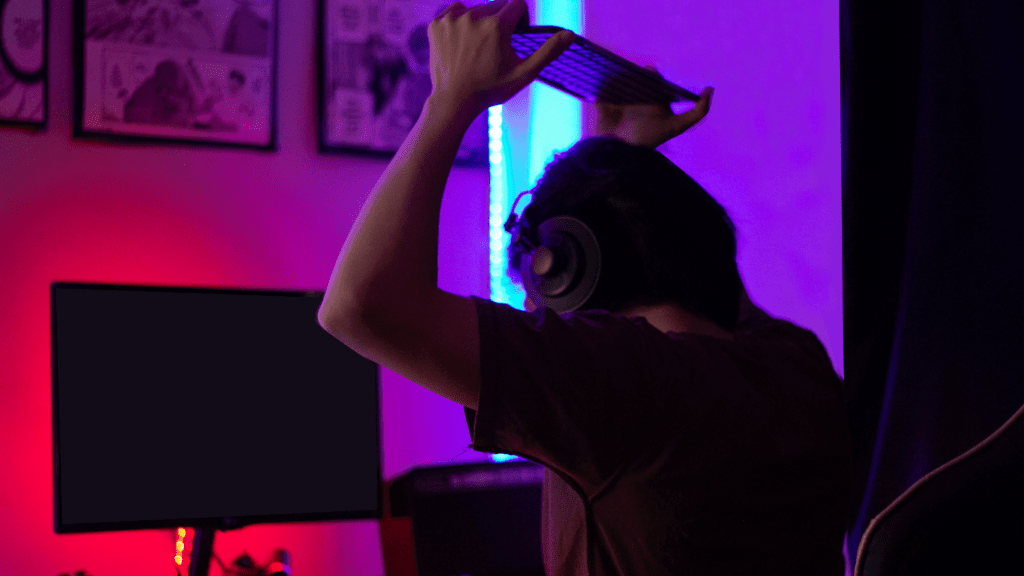 A person playing video games in a dark room wearing a headset