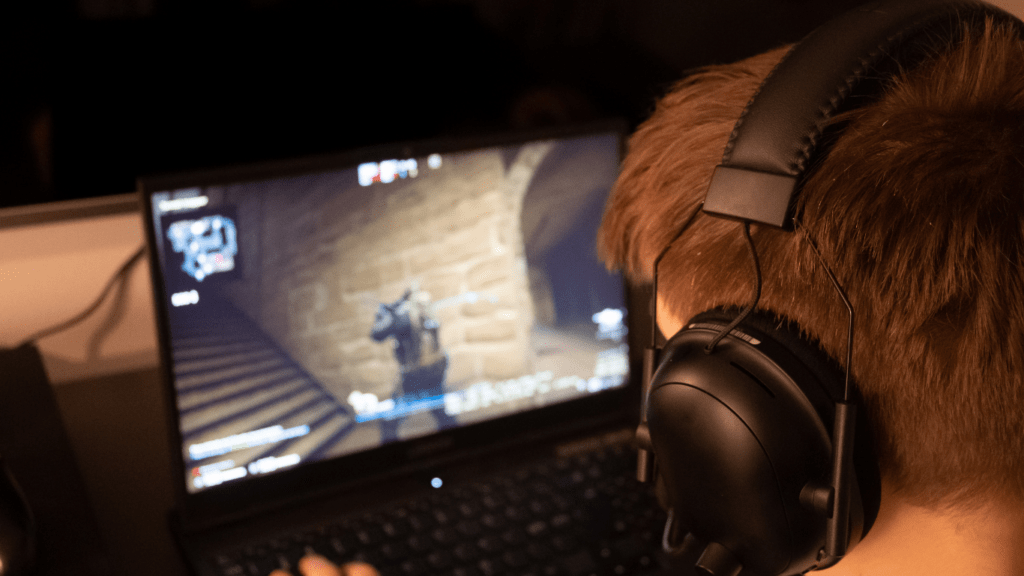 A person wearing headphones is playing a video game on a computer