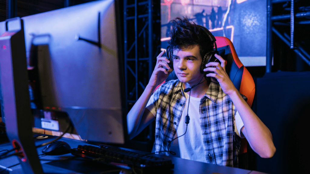 A person playing video games in a dark room wearing a headset