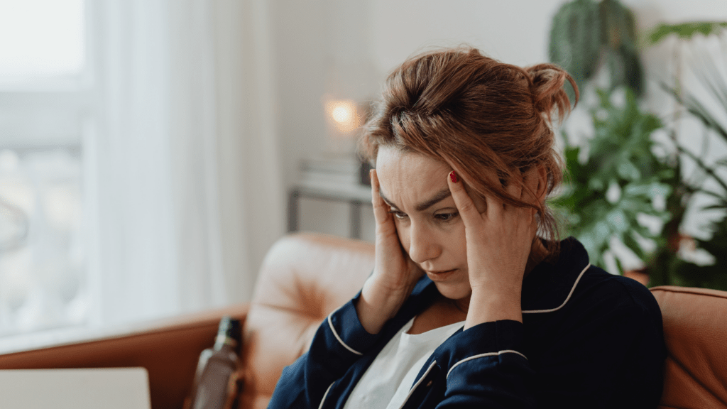 a person sitting in front of a laptop with their head in their hands