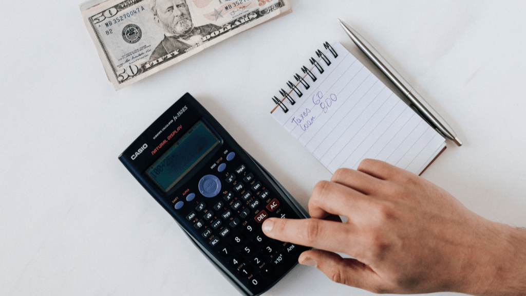 calculator, pen, money and notepad on white table