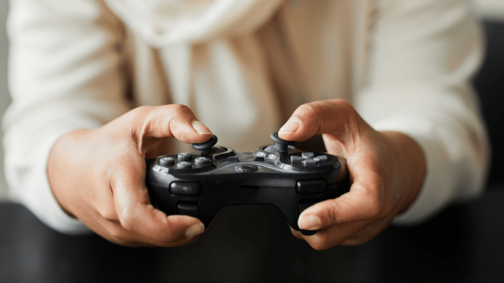 A person holding a video game controller in front of neon lights