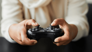 A person holding a video game controller in front of neon lights