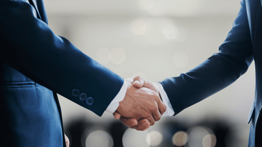 two business people shaking hands over a desk