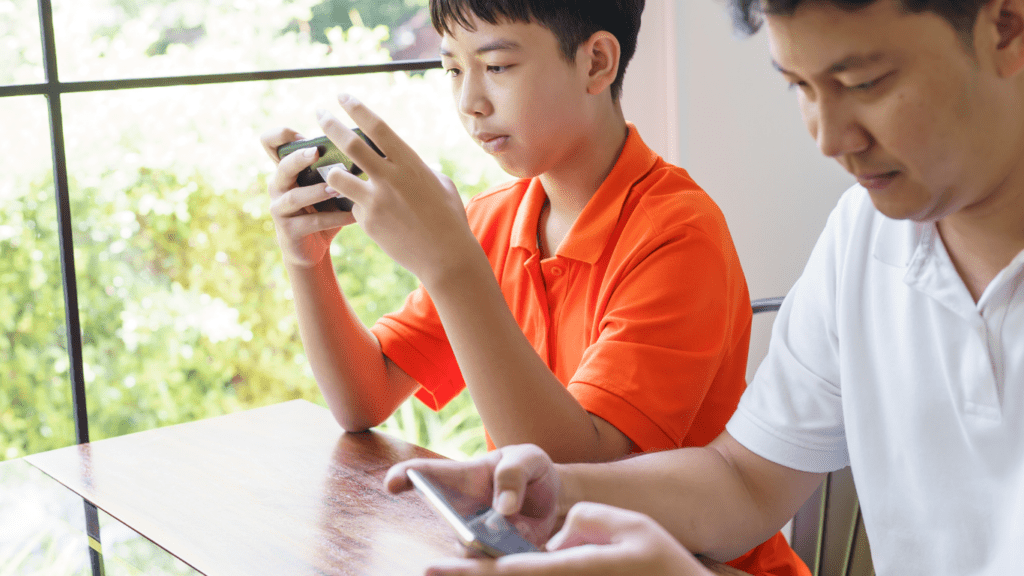 Two people sitting at a table using a cell phone