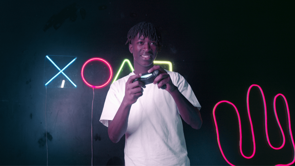a person holding a video game controller in front of a neon sign