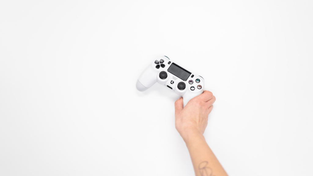 a person holding a video game controller in front of a white wall