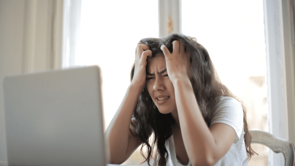 a person sitting in front of a laptop with their head in their hands