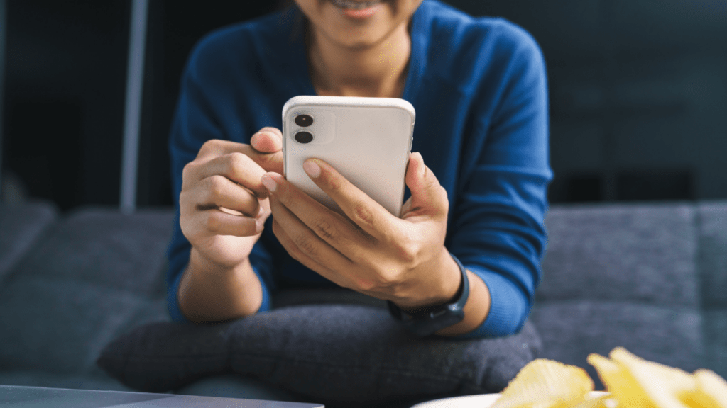 a person sitting on a couch holding a cell phone