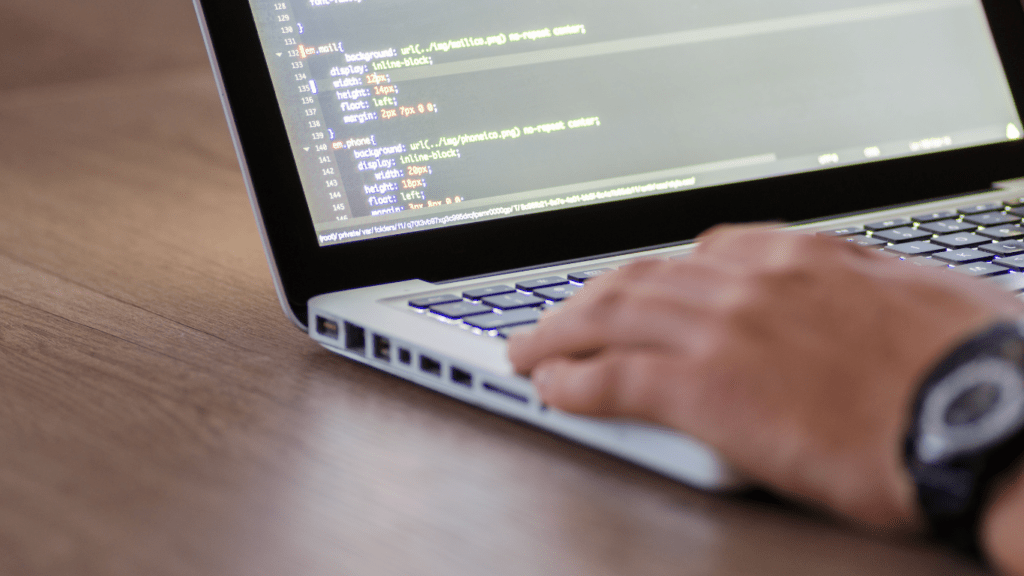 a person typing on a laptop with code on the screen