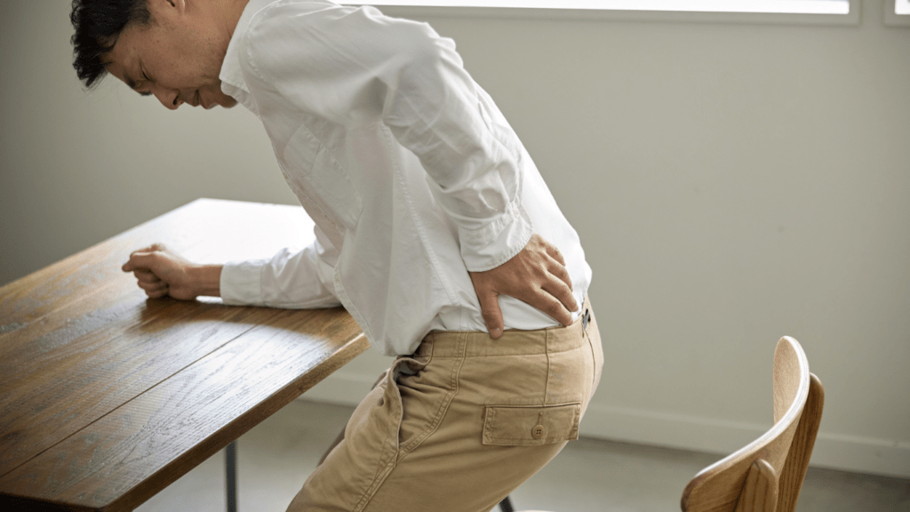 a person with back pain sitting at a desk