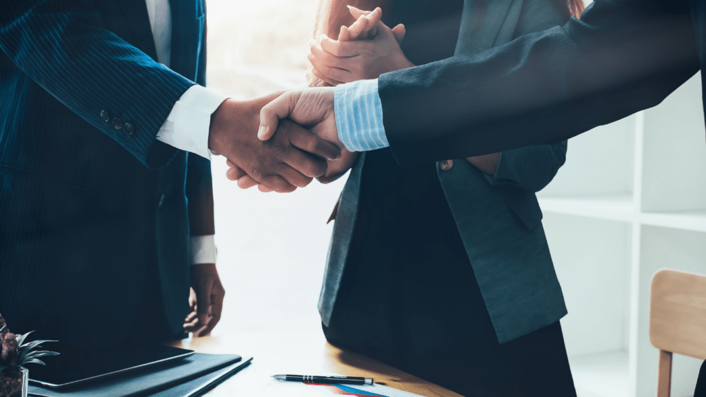 two business people shaking hands over a desk