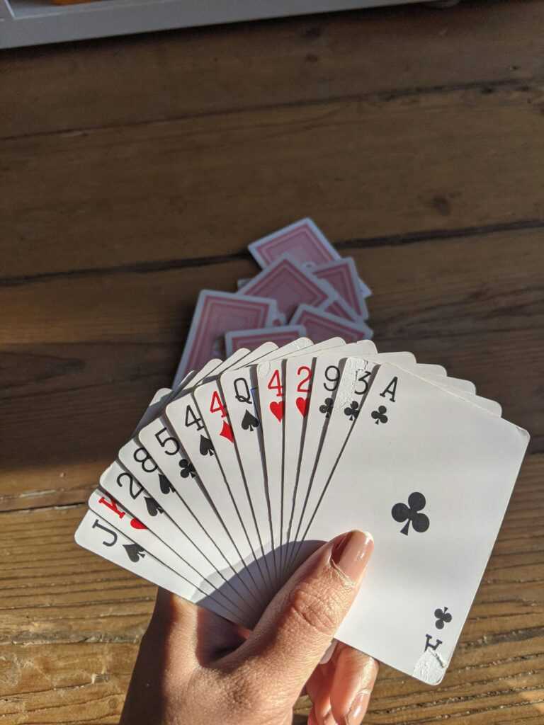 A close-up of a hand holding a fan of playing cards on a wooden table, perfect for gambling themes.